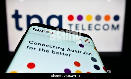 Mobile phone with website of Australian company TPG Telecom Limited on screen in front of business logo. Focus on top-left of phone display. Stock Photo