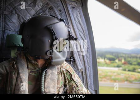 Hawaii Army National Guard Sgt. Nicholas Pa, a CH-47 Chinook crew chief assigned to Company Bravo, 2nd Battalion, 211th Aviation Regiment, 103rd Troop Command stares out the window during a flight at Schofield Barracks, Hawaii, April 2, 2022. The 211th conducted sling load operations with 1st Battalion, 487th Field Artillery Regiment, 29th Infantry Brigade Combat Team. Stock Photo