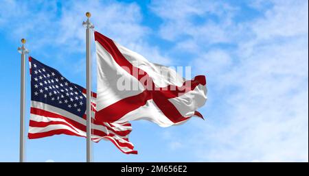 The flag of the state of Alabama waving alongside the national flag of the United States on a sunny day. The flag of Alabama features a red cross on a Stock Photo