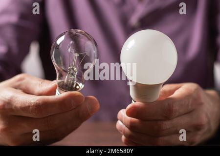 Two lamps in the hands of a man. Incandescent light bulb and LED light bulb in your hands. Close-up. Stock Photo