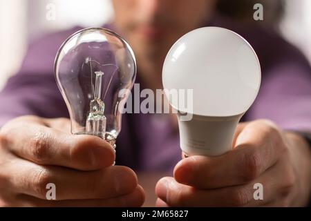 Two lamps in the hands of a man. Incandescent light bulb and LED light bulb in your hands. Close-up. Stock Photo