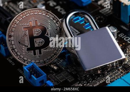 Bitcoin with locker on motherboard. Cryptocurrency law. Digital security. BTC banned. Stock Photo