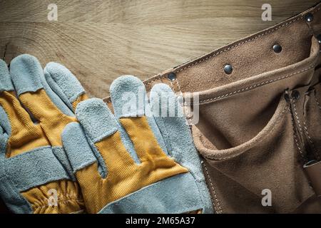 Leather tool belt safety gloves on wooden board. Stock Photo