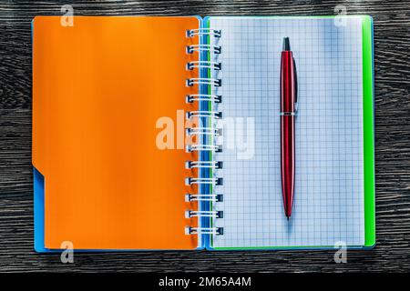 Pen spiral checked notebook on vintage wooden board. Stock Photo