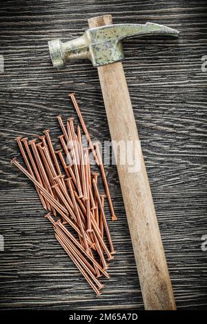 Pile of brass nails claw hammer on wooden board. Stock Photo