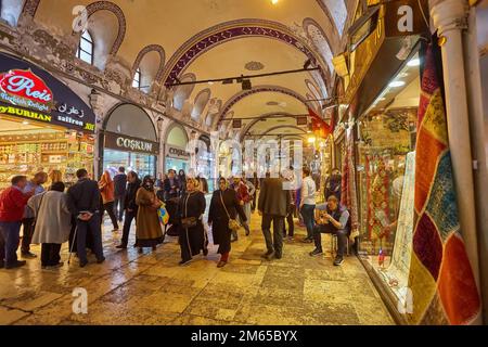 ISTANBUL, ISTANBUL - APRIL 21, 2017: People shopping in the Grand Bazar, handmade pillows, bags and carpets are on the wall for sale. The sunlight com Stock Photo