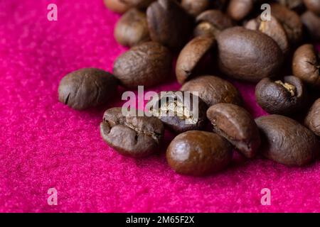 Close up image of fresh brown roasted coffee beans on a vivd magenta background. Copyspace below left. Stock Photo
