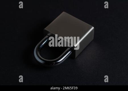 Steel padlock on the black textured background. Stock Photo