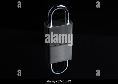 Steel padlock on the black textured background. Stock Photo