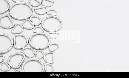 Metal accessories and supplies for bags, backpacks and sewing laying on a grey background. Chrome-plated metal frames for handbags straps. Sewing, bag Stock Photo