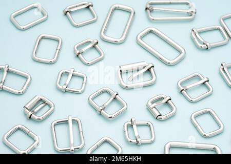Metal adjusters and frames for making bags and backpacks on light blue background. Chrome-plated metal frames for handbags straps. Sewing accessories Stock Photo
