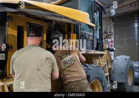 U.S. Air Force Tech. Sgt. Chris Knight, left, customer service non-commissioned officer in charge of the Vehicle Management Flight, 386th Expeditionary Logistics Readiness Squadron, and Staff Sgt. Garrett Goss, customer service representative, 386th ELRS, lubricate the hinges of a Caterpillar front bucket loader at Ali Al Salem Air Base, Kuwait, April 4, 2022. As the final hands on the vehicle before it went back to the customer, they performed a quality check and added any finishing touches. ELRS,VCO,maintenance,mechanic,vehicle management, Stock Photo