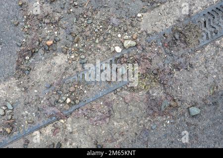 Drainage channel or channel drain blocked with soil and gravel unable to be used to direct rainwater from road due to lack of maintenance Stock Photo