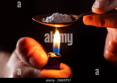 Drug addicts in the dark room. Addict preparing drugs with a spoon and lighter. White powder and a syringe. Drug concept. International drug abuse day Stock Photo