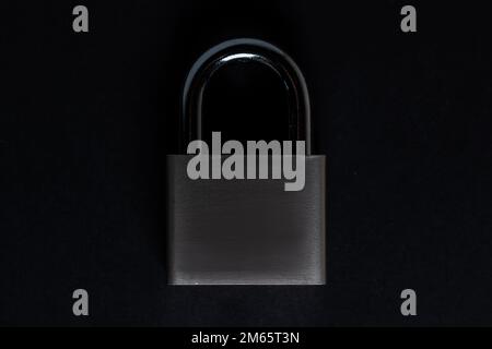 Steel padlock on the black textured background. Stock Photo