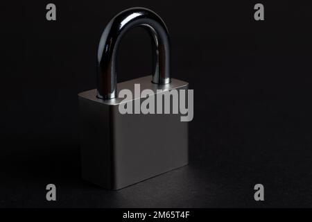 Steel padlock on the black textured background. Stock Photo