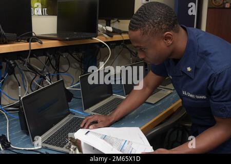 U.S. Coast Guard Petty Officer 3rd Class Carl Taylor, an information systems technician assigned to Electronics Support Detachment Mayport, Florida, reimages newly assigned laptops delivered to Coast Guard Sector Jacksonville, Florida, April 5, 2022. Reimaging new computers involves completely wiping the hard drive, and installing the operating system along with Coast Guard-specific applications and security-related upgrades. PC,upgrade,workstation, Stock Photo