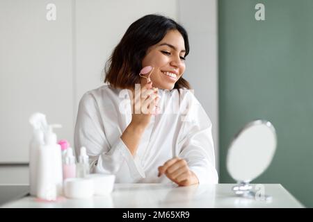 Happy woman using natural stone massager, enjoying healthy glowing skin Stock Photo