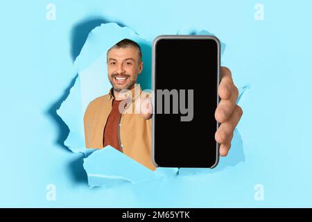 Happy middle aged man holding smartphone with blank screen, showing gadget with copy space for mockup Stock Photo