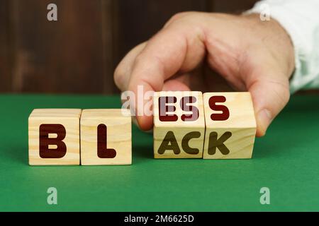 Education concept. On a green surface, a man puts cubes with the inscription - BLESS, BLACK Stock Photo