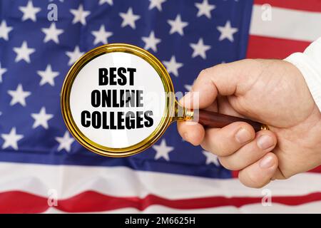 In front of the American flag, a man holds a magnifying glass in his hand with the inscription - Best Online Colleges. Stock Photo