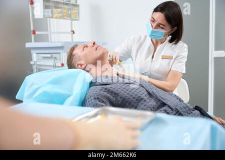 Aging gentleman having great skin treatment by injection at clinic Stock Photo