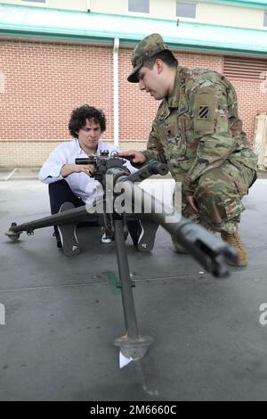 U.S. Army Spc. Ernesto Alverado, a unit supply specialist assigned to the 287th Quartermaster Field Feeding Company, 3rd Division Sustainment Brigade, 3rd Infantry Division, explains the process of loading a M2A1 Machine Gun to Phillip Scroggin, an ambassador for Richmond Hill-Bryan County chamber of commerce, during a combined leadership tour at Fort Stewart, Georgia, April 6, 2022.  The combined leadership tour helps provide a conceptual understanding of Soldier operations within their community to help them become advocates, stakeholders and good neighbors. (U.S. Army Photos by Sgt. Aaliyah Stock Photo