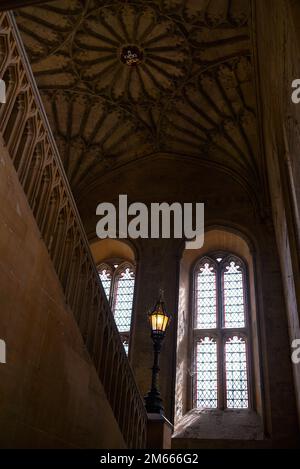 The Grand Staircase and fan vaulted ceiling at Christ Church College in Oxford, England, highlighted in red trim Gothic windows. Stock Photo