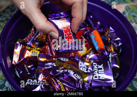 Hand picking out Heroes chocolate from tin Stock Photo