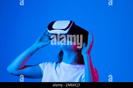 Impressed brunette woman using virtual reality headset, getting immersed experience, interacting with immersive digital world, testing VR technology Stock Photo