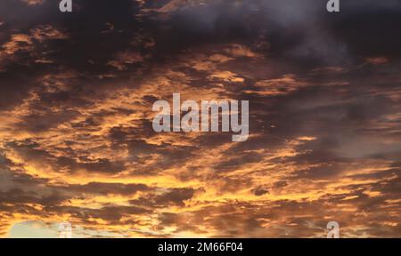 Dramatic golden cloudy sky. Sun rays through the dark clouds Stock Photo