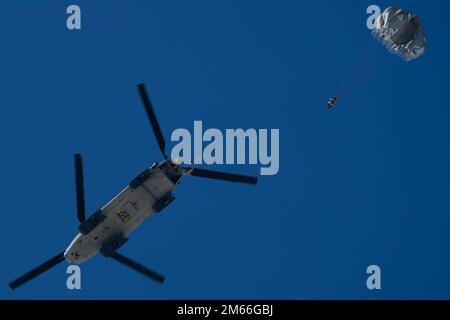 U.S. Air Force tactical air control party (TACP) specialists assigned to Detachment 1, 3rd Air Support Operations Squadron, descend after jumping from a U.S. Army CH-47 Chinook helicopter assigned to B Company, 2-211th General Support Aviation Battalion, Alaska Army National Guard, at Joint Base Elmendorf-Richardson, Alaska, April 7, 2022. The jump took place on Geronimo Drop Zone to build airborne and mission-readiness skills in an arctic environment. Stock Photo