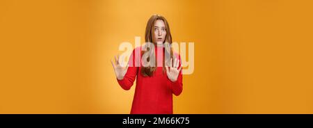 Intense panicking and freaked out girl with red hair asking slow down, raising hands near chest in stop and not gesture open mouth surpised and Stock Photo