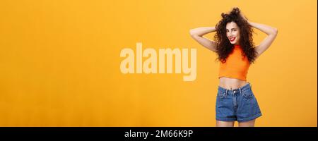 Woman posing for boyfriend being pleased with new look after visiting hairdresser touching curly hairstyle flirty and carefree smiling sensualy Stock Photo