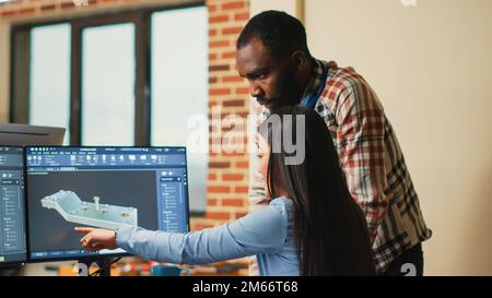 Creative 3D artists discussing about machinery development, working together on clamp prototype. Professional graphic engineers developing industrial engine product using specialized software. Stock Photo