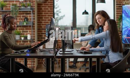 Professional office workers analyzing blueprint project on multi monitors, using engineering software on pc. Creative designers developing art on computer, discussing about 3D technology. Stock Photo