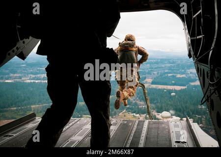 Washington National Guard Soldiers with 1st Battalion, 168th General Support Aviation Regiment (GSAB), 96th Aviation Troop Command, transport 1st Special Forces Group (Airborne) and Canadian partners over Rogers Drop Zone on Joint Base Lewis-McChord, Wash., Dec. 6, 2022. The joint static line jump was part of the 78th Annual Menton Week celebrations commemorating the anniversary of the combined U.S. and Canadian First Special Service Force deactivation. (U.S. Army National Guard photo by Staff Sgt. Adeline Witherspoon) Stock Photo