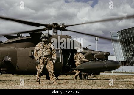 A U.S. Army Soldier with 1-214th General Support Aviation Battalion, 12th Combat Aviation Brigade stands in front of a UH-60 Blackhawk helicopter also from 1-214th GSAB, 12 CAB as they wait for Soldiers to load up during a joint exercise led by the Polish Armed Forces at the landing zone near the G2A Arena, Poland, April 8, 2022. This exercise and others like it enhances our interoperability with our NATO allies and partners and strengthens the regional relationships that we have developed. 12 CAB is the only enduring aviation brigade present throughout Europe that enables us to deter and defe Stock Photo