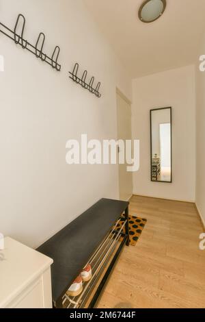 a living room with white walls and wood flooring on the wall, there is a mirror hanging above it Stock Photo