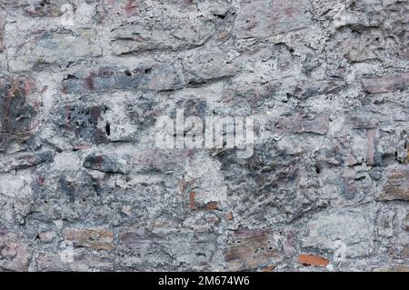 Stone wall background closeup, horizontal plastered grunge red grey beige stonewall limestone pattern, old aged weathered gray lime plaster texture Stock Photo