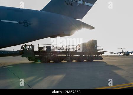 A Tunner 60K aircraft cargo loader delivers cargo to a U.S. Air Force C-17 Globemaster III during readiness exercise Roundel Perun 22-01, Travis Air Force Base, California, April 10, 2022. The base exercise was designed to enhance the capabilities of multiple squadrons in responding to possible real-world scenarios. Stock Photo