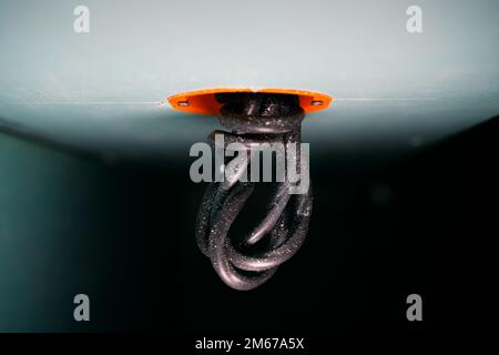 Close-up of a thick black wire sticking out of an orange round drywall socket. Mortgage for a socket or switch with a wire. Electrical wiring for repa Stock Photo