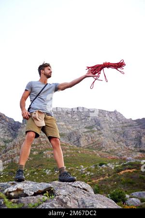 Dont forget your rope. Full length shot of a handsome young man throwing a rope while hiking. Stock Photo