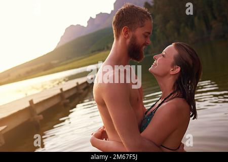 Never let you go...an affectionate young couple hugging while swimming in a lake. Stock Photo