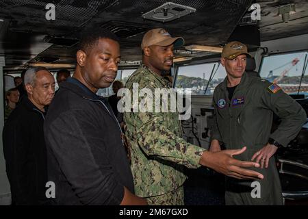 220412-N-SI601-1180 YOKOSUKA, Japan (April 12, 2022) Capt. Justin Issler, executive officer, right, and Quartermaster 2nd Class Shamir Lane, center, from Philadelphia, give Maj. Gen. Lloyd Miles, U.S. Army Ret., Senior Vice President, Global Military Operations, far left, and Dr. Gregory Fowler, President, University of Maryland Global Campus, a tour of the bridge aboard the U.S. Navy’s only forward-deployed aircraft carrier USS Ronald Reagan (CVN 76). The University of Maryland Global Campus provides educational opportunities to service members stationed around the world. Ronald Reagan, the f Stock Photo