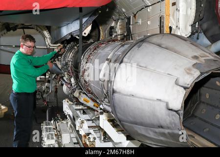 Aviation Machinist's Mate 3rd Class Revera Dario, from Los Angeles, assigned to the 'Gray Wolves' of Electronic Attack Squadron (VAQ) 142, conducts routine maintenance on the engine of an E/A-18G Growler in USS Gerald R. Ford’s (CVN 78) hangar bay, April 12, 2022. Ford is underway in the Atlantic Ocean conducting carrier qualifications and strike group integration as part of the ship’s tailored basic phase prior to operational deployment. Stock Photo