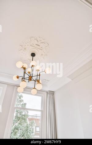 a room with white walls and light fixtures hanging from the ceiling to the floor, there is a large window Stock Photo