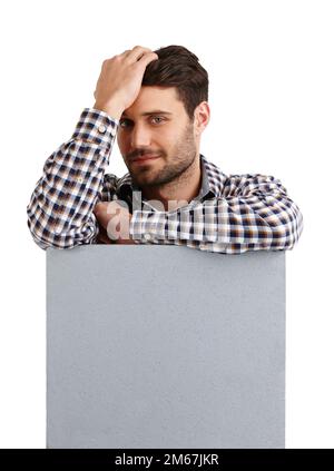 Making your copyspace look good. Studio portrait of a handsome young man leaning on a blank placard isolated on white. Stock Photo