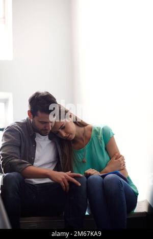 There when she needs a shoulder to cry on. a man comforting a distressed woman in a stairwell. Stock Photo