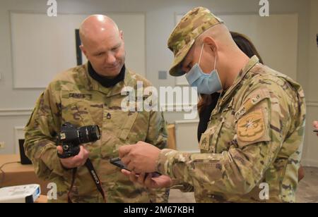 Sgt. Audino Saavedra (Servicio Nacional Aeronaval or SENAN), shows Sgt. 1st Class Joel Combs (3175th MP Co. a photo taken with his cell phone during a Macro-photography practical exercise. The exercise was a part of a National Guard Bureau State Partnership Program Subject Matter Expert Exchange on crime scene investigation in Panama City 12-14 April, 2022. Stock Photo